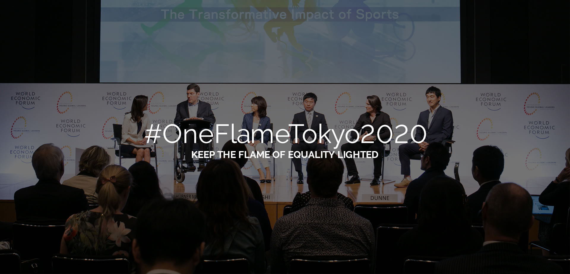 #OneFlameTokyo2020 Mantenha a chama da igualdade acesa. Vista em primeiro plano da platéia, de costas, e ao fundo as seis pessoas no palco do World Economic Forum em Tóquio.